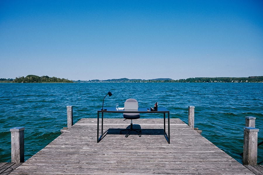 A desk and chair on a pier in a Bavarian lake.