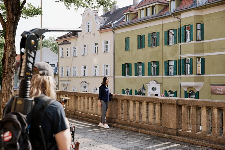 An Asian woman is filmed by a cameraman in an urban environment