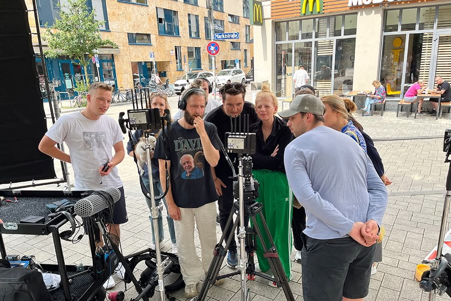 Film crew standing on a street watching the footage they have just filmed