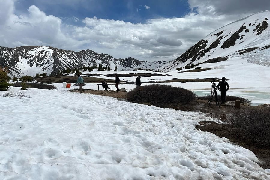 Film crew building a set in a snowy mountain landscape