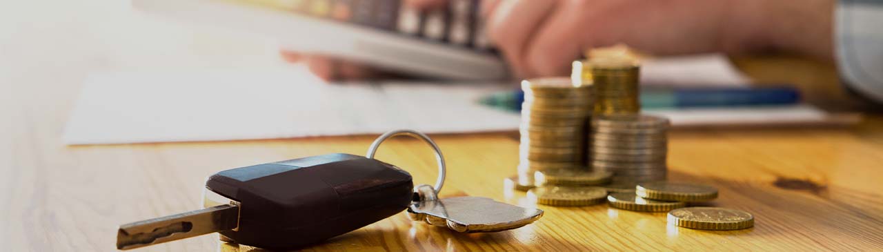Car keys and money on table with a man using a calculator.