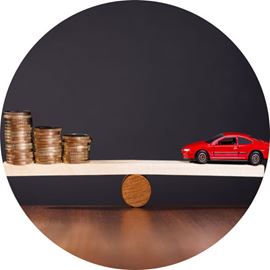 Scale with cash on one side and a red car on the other side.