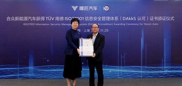 TÜV南德丛瑛（左一）向哪吒汽车彭庆丰颁发ISO 27001信息安全管理体系认证证书